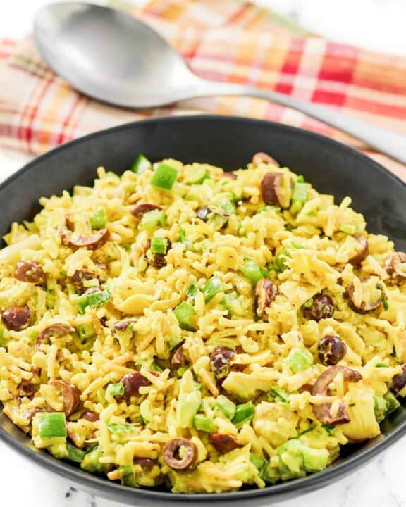 Rice-A-Roni artichoke salad with curry in a large bowl and a large spoon behind it.