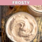 Homemade Wendy's chocolate frosting in a glass on top of a wood board.