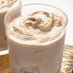 Homemade Wendy's chocolate frosty in glasses on a wood board.