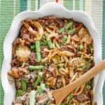 Hamburger green bean casserole in a dish and on a wooden spoon.